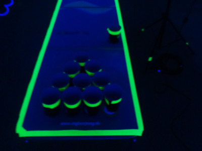 EVINTA_Teambuilding_Teamspiel Becher Pong_Spieltisch mit Bechern in Schwarzlicht